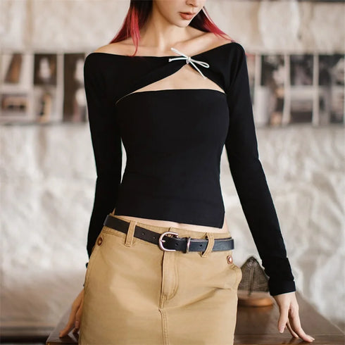 Person wearing a black long-sleeve top with a cutout design and beige pants in an indoor setting.